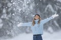 With arms wide open, woman in blue sweater, white gloves, scarf and hat enjoys fresh air on a snowy winter day Royalty Free Stock Photo