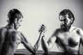 Arms wrestling thin hand, big strong arm in studio. Two man`s hands clasped arm wrestling, strong and weak, unequal