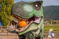 Close-up portrait of Tyrannosaurus Rex statue holding pumpkin in mouth in autumn