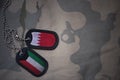 army blank, dog tag with flag of bahrain and kuwait on the khaki texture background.