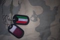 army blank, dog tag with flag of kuwait and qatar on the khaki texture background.