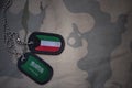 army blank, dog tag with flag of kuwait and saudi arabia on the khaki texture background.