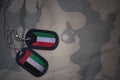 army blank, dog tag with flag of kuwait and united arab emirates on the khaki texture background.