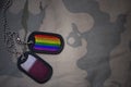 army blank, dog tag with flag of qatar and gay rainbow flag on the khaki texture background.