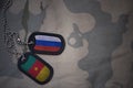 army blank, dog tag with flag of russia and cameroon on the khaki texture background.