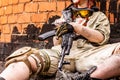 Army girl with rifle in camouflage clothes in urban scene, getting rest. Croped portrait, close up