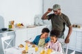 Army soldier father looking at happy kids enjoying meal