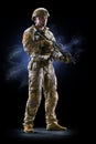 Army soldier in Protective Combat Uniform holding Special Operations Forces Combat Assault Rifle on dark background