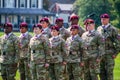 Army soldiers in the airborne division wearing their military camouflage and red berets stand at attention on the parade field