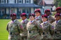 Army soldiers in the airborne division wearing their military camouflage and red berets stand at ease on the parade field