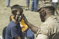 Army solider applying camouflage to young boy