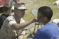 Army solider applying camouflage to young boy