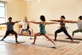 An army of yoga warriors. a group of young men and women practicing the warrior pose pose during a yoga session. Royalty Free Stock Photo