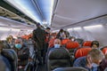 A lot of air passengers with mask sitting on airplane seats and making final preparations before takeoff time in Turkish Airlines