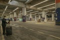 Old man with masks and luggage and passengers with bags waiting for bus after flight underground in bus stop in Istanbul Airport