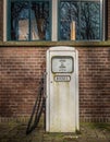 Isolated classic old white gas pump in front of a brick wall