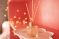 Aroma fragrance in bottle with sticks over lights close up. Home cozy atmosphere