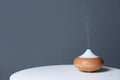 Aroma oil diffuser lamp on table against gray background. Royalty Free Stock Photo