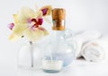 Aroma oil, orchid and candle on white table. Blurred towels in background Royalty Free Stock Photo