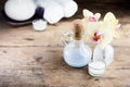 Aroma oil, orchid and candle on wooden table. Blurred massage bags and towels in background Royalty Free Stock Photo