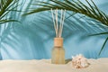Aroma reed diffuser glass bottle on the sea beach in the summer morning