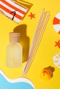 Aroma reed diffuser glass bottle on yellow summer background with sand and sea