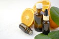 Aromatherapy concept with essential oil bottles, fresh orange and tropical leaves on white background.