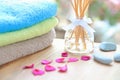 Aromatherapy reed difuser bottle on a wooden table with towels, petals and massage stones Royalty Free Stock Photo