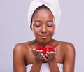 Aromatherapy at the spa. A studio shot of a beautiful young woman holding red petals and wearing a towel on her head. Royalty Free Stock Photo