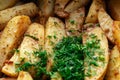 Aromatic baked potato wedges with fresh dill herbs. Homemade rustic dish, delicious hearty food close up