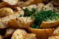 Aromatic baked potato wedges with fresh dill herbs. Homemade rustic dish, delicious hearty food close up