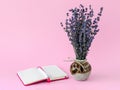 Aromatic bouquet of dry lavender in a beautiful ceramic vase and white ballpoint pen on the opened lined paper notepad in a pink