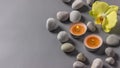 Aromatic candles, orchid flower and stones on a gray background. Spa composition. Relaxation and zen like concept