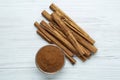 Aromatic cinnamon powder in bowl near sticks on white wooden table, flat lay Royalty Free Stock Photo