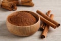 Aromatic cinnamon powder in bowl and sticks on white wooden table, closeup Royalty Free Stock Photo