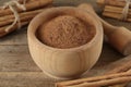 Aromatic  cinnamon powder in mortar, sticks and pestle on wooden table, closeup Royalty Free Stock Photo