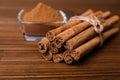 Aromatic cinnamon sticks and glass bowl with powder on wooden table, closeup Royalty Free Stock Photo