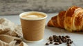 Aromatic coffee in a paper cup paired with a flaky croissant