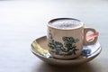 Aromatic frothy coffee served in traditional chinese cup and saucer in kopitiam against backlight