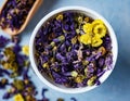 Aromatic herbal dry tea lavender and chamomile loose near white cup on blue wood table macro