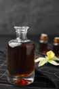 Aromatic homemade vanilla extract in glass bottle on table
