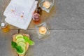Aromatic oil, burned candle, pink flowers, sliced lime, green leaf, white towel on vintage grunge stone background