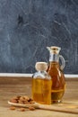 Aromatic oil in a glass jar and bottle with almond in a scoop on wooden table, close-up. Royalty Free Stock Photo