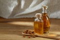 Aromatic oil in a glass jar and bottle with almond in a scoop on wooden table, close-up. Royalty Free Stock Photo