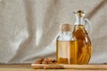 Aromatic oil in a glass jar and bottle with almond in a scoop on wooden table, close-up. Royalty Free Stock Photo