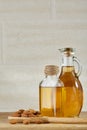 Aromatic oil in a glass jar and bottle with almond in a scoop on wooden table, close-up. Royalty Free Stock Photo