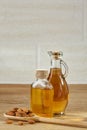 Aromatic oil in a glass jar and bottle with almond in a scoop on wooden table, close-up. Royalty Free Stock Photo