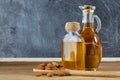 Aromatic oil in a glass jar and bottle with almond in a scoop on wooden table, close-up. Royalty Free Stock Photo