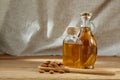 Aromatic oil in a glass jar and bottle with almond in a scoop on wooden table, close-up. Royalty Free Stock Photo