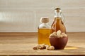 Aromatic oil in a glass jar and bottle with peanuts in bowl on wooden table, close-up. Royalty Free Stock Photo
